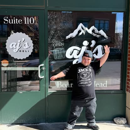 AJ's employee posing in front of deli